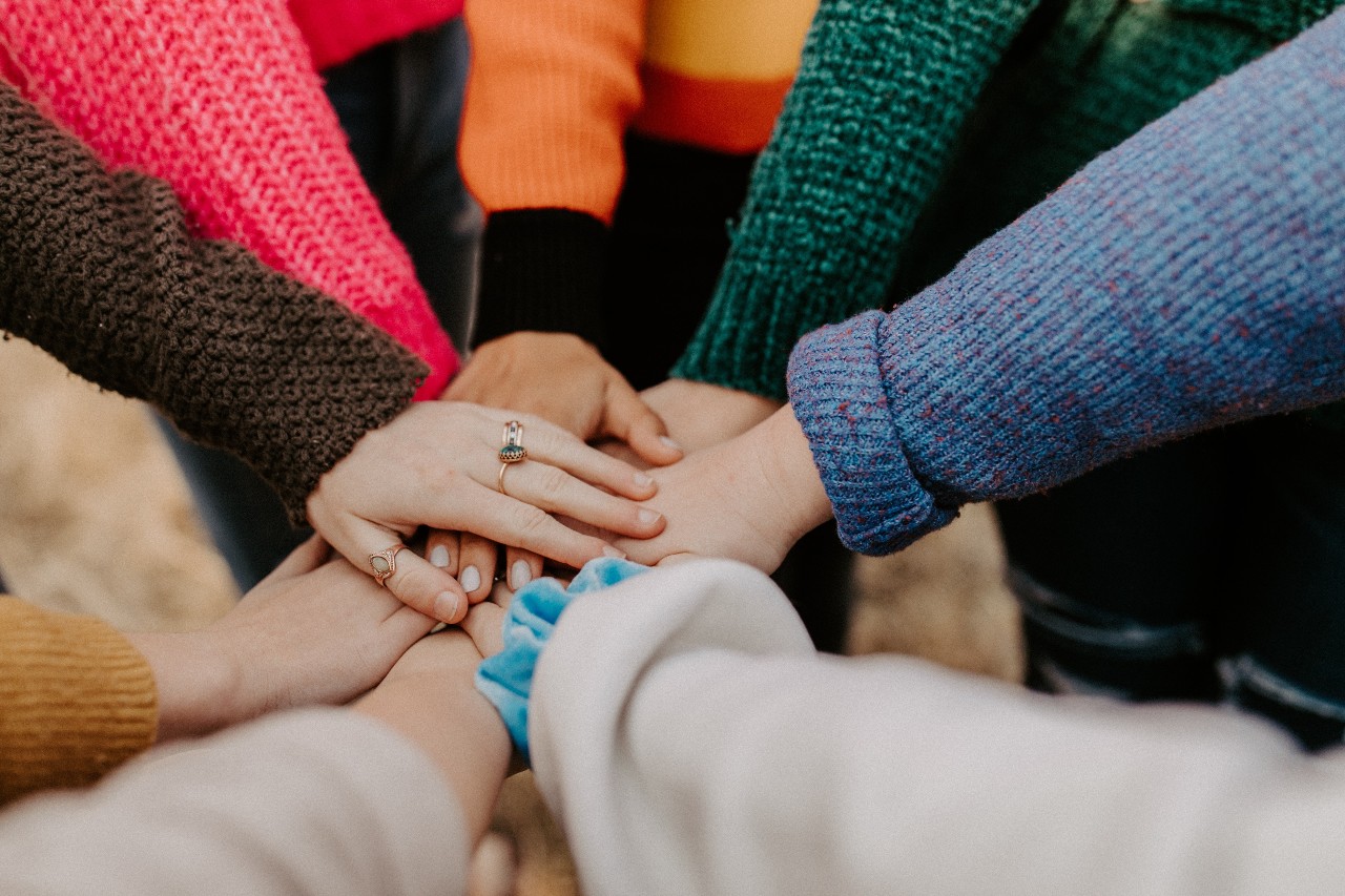 Several hands over the top of each other in an 'all-in' gesture